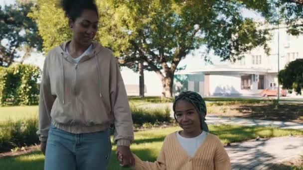 美しいアフリカ系アメリカ人の女の子が手を取りながら公園を歩いている — ストック動画