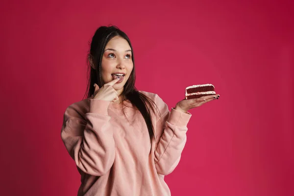 アジアの幸せな女性なめる彼女の指でポーズとともにケーキ孤立以上紫壁 — ストック写真