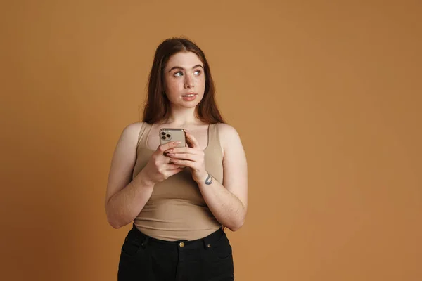 Jovem Mulher Gengibre Usando Telefone Celular Olhando Para Lado Isolado — Fotografia de Stock