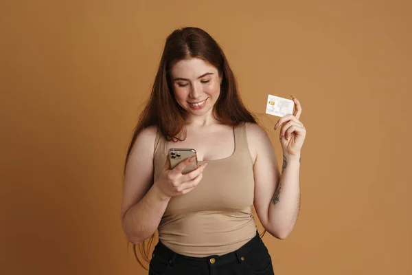 Uśmiechnięta Młoda Kobieta Size Trzymająca Telefon Komórkowy Kartę Kredytową Stojąc — Zdjęcie stockowe