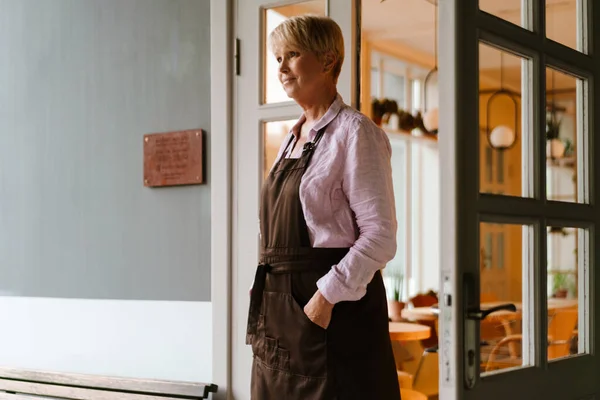 Ώριμη Γυναίκα Που Φοράει Ποδιά Και Στέκεται Στην Καφετέρια — Φωτογραφία Αρχείου