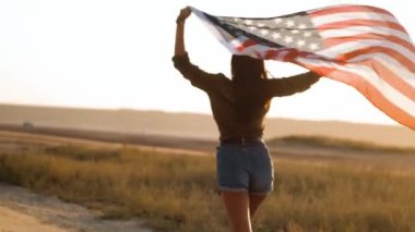 Bir kadının arkası, yaz aylarında elinde bir Amerikan bayrağıyla koşuyor.