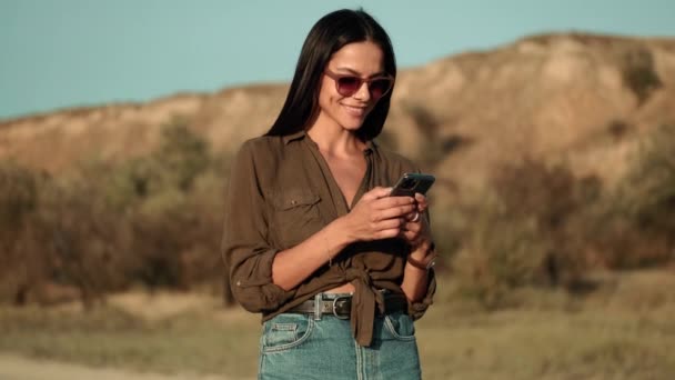 Een Aantrekkelijke Vrouw Met Een Zonnebril Gebruikt Haar Smartphone Tijdens — Stockvideo