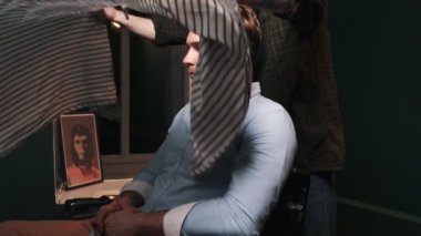 Yetenekli bir berberin kırpılmış görüntüsü, berber dükkanında saç kesmeden önce müşterisine önlük giydirmektir.