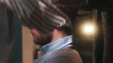 Hipster dövmeli berber berber, berber dükkanında saç kesmeden önce müşterisine önlük takıyor.