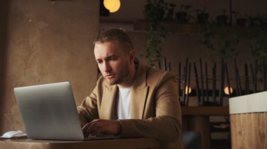 Kafede laptopunu kullanırken faturayla çalışan ciddi bir beyaz işadamı.