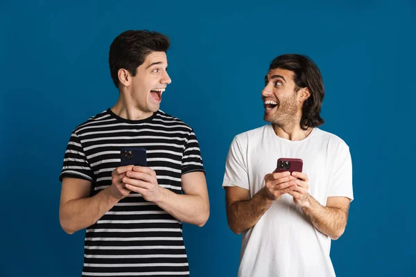 Excitado Dois Homens Gritando Usar Celulares Isolados Sobre Fundo Azul — Fotografia de Stock