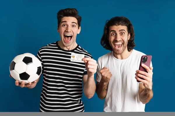 Excitado Dois Homens Usando Celular Enquanto Segurando Futebol Cartão Crédito — Fotografia de Stock