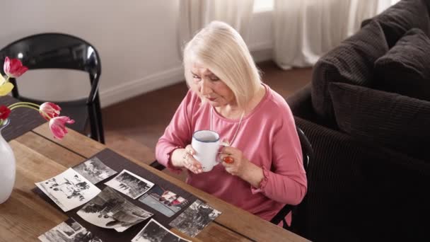 Une Femme Âgée Regardant Vieilles Photos Autour Une Tasse Thé — Video