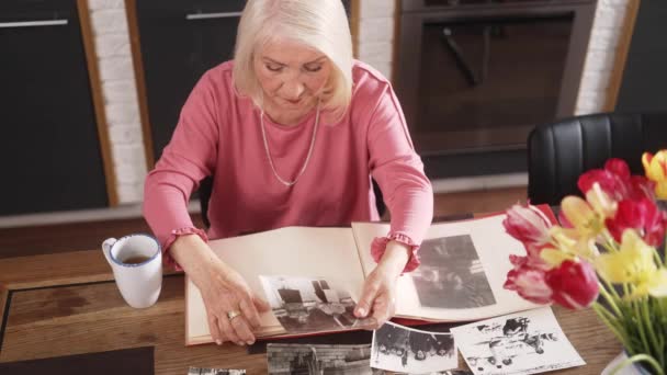 Una Anciana Insertando Fotos Viejas Álbum Mientras Está Sentada Cocina — Vídeo de stock