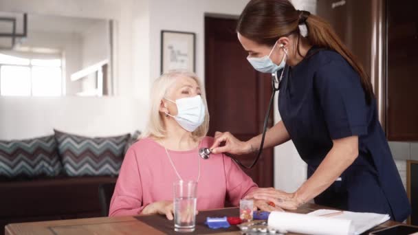 Eine Lächelnde Ärztin Schützender Einmalmaske Hört Mit Einem Stethoskop Ihrem — Stockvideo