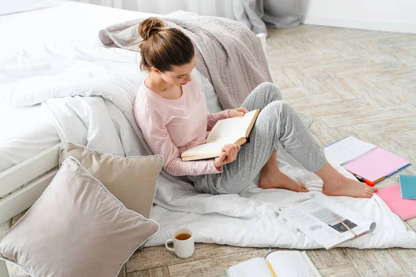Молодая Белая Женщина Читает Книгу Сидя Полу Своей Спальни Одеяле — стоковое фото