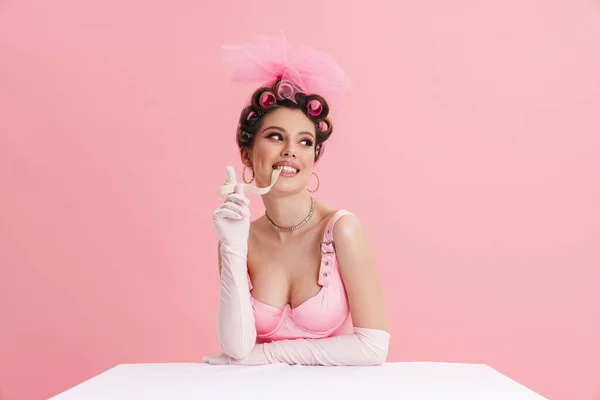 Улыбающаяся Женщина Перчатках Ест Зефир Сидя Столом Розовом Фоне — стоковое фото