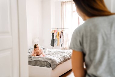 White woman looking at her daughter with down syndrome in bedroom at home