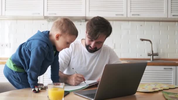 Ein Ernsthafter Vater Arbeitet Tisch Während Sein Kleiner Sohn Neben — Stockvideo