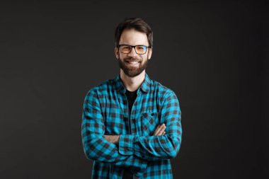 Gözlüklü mutlu adam, gülümsüyor ve siyah arka planda izole edilmiş kameraya bakıyor.