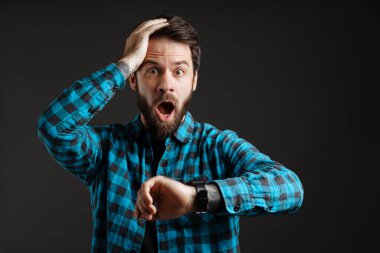 Sakallı beyaz adam siyah arka plandan izole edilmiş kol saatine bakarken haykırıyor.