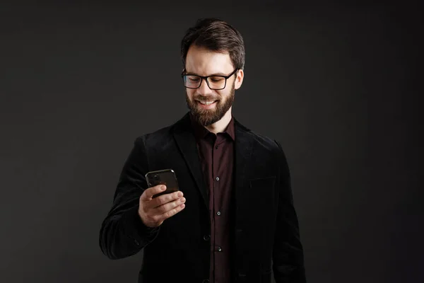 Brodaty Szczęśliwy Człowiek Kurtce Uśmiecha Się Podczas Korzystania Telefonu Komórkowego — Zdjęcie stockowe