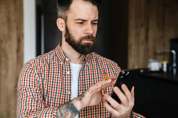 Serious Brunette Bearded Man Looking Mobile Phone His Hands Standing — Stock Photo, Image