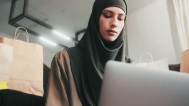 Yoğunlaştırılmış Arap bir kadın evine paket göndermeden önce dizüstü bilgisayarını kullanıyor.