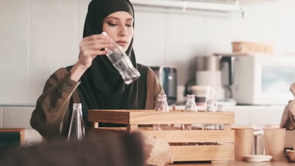 Seorang Wanita Arab Yang Cantik Menempatkan Botol Kaca Dalam Wadah — Stok Video