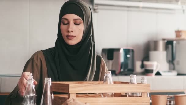 Seriøs Arabisk Kvinde Lægger Glasflasker Træbeholderen Mens Hun Sorterer Skraldet – Stock-video