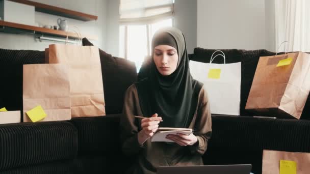 Serious Arabian Woman Making Notes Sending Parcel Sitting Home — Stock Video