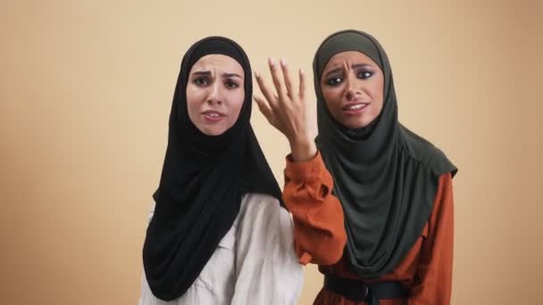 两名身穿民族头巾的愤怒的阿拉伯妇女一边看着站在因米黄色背景而与世隔绝的摄影棚里的摄像机 一边咒骂着 一边火冒三丈 — 图库视频影像