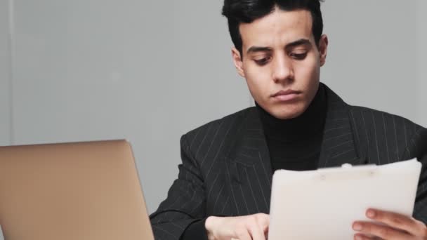 Myślący Arabski Człowiek Używa Laptopa Trzymając Papierowe Dokumenty Biurze — Wideo stockowe