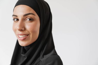 Beyaz stüdyodaki tesettürdeki tesettürlü Müslüman kadının yakın çekim görüntüsü.