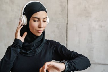 Kulaklıklı genç müslüman sporcu kadın ve içeride akıllı bakışlara bakıyor.