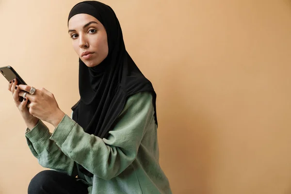 Мусульманка Хіджабі Тримає Телефон Дивиться Камеру Стоячи Помаранчевій Студії — стокове фото