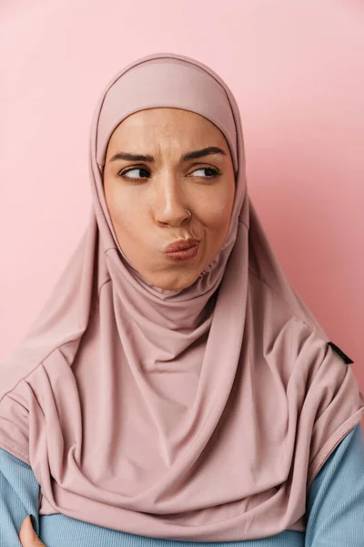 ピンクのヒジャーブを着てピンクのスタジオに立ちながら何かを考えるムスリム女性の肖像画 — ストック写真