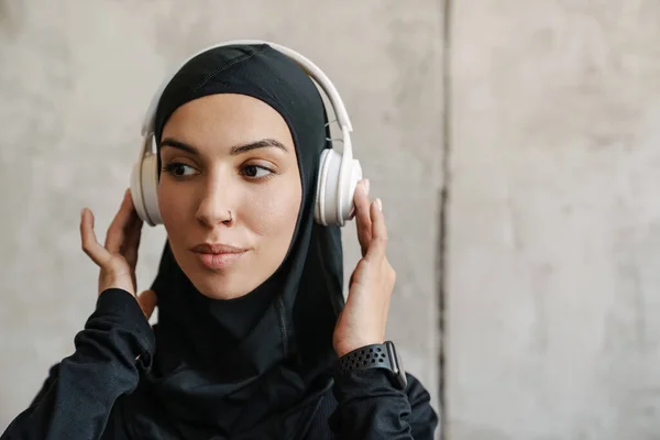 Nuori Muslimi Urheilija Hijabissa Kuuntelee Musiikkia Kuulokkeilla Sisätiloissa — kuvapankkivalokuva