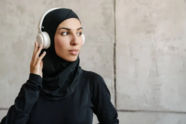 Nuori Muslimi Urheilija Hijabissa Kuuntelee Musiikkia Kuulokkeilla Sisätiloissa — kuvapankkivalokuva