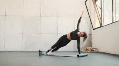 Bacak protezi olan odaklanmış bir kadın bir stüdyoda yoga minderinde yoga egzersizleri yapıyor.