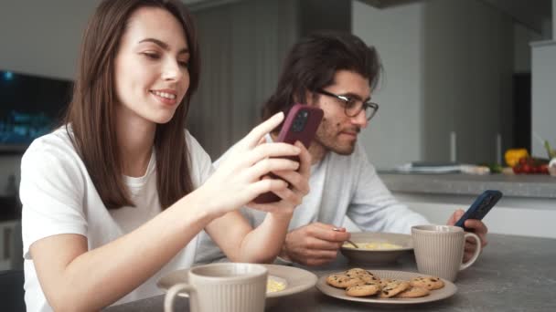 Gülümseyen Bir Çift Içeride Kahvaltı Ederken Cep Telefonlarını Kullanıyor — Stok video