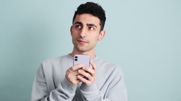 Brunette Man Holding His Mobile While Thinking Something Standing Isolated — Stock Video