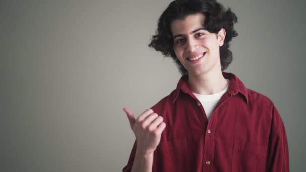 Hombre Moreno Sonriente Con Una Camisa Roja Señala Con Dedo — Vídeos de Stock