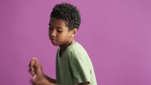 Egy Boldog Kisfiú Zöld Pólóban Egyedül Táncol Lila Háttér Felett — Stock videók