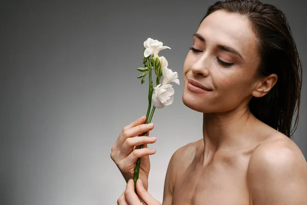Gri Arkaplanda Beyaz Çiçekle Poz Veren Beyaz Üstsüz Bir Kadın — Stok fotoğraf