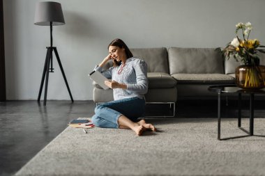 Orta yaşlı kadın evde bir kanepede dinlenirken dijital tablet kullanıyor.