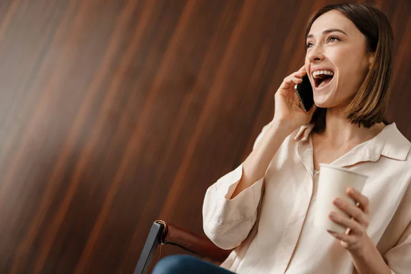 Kahve Içen Cep Telefonuyla Konuşan Heyecanlı Bir Kadın Koltukta Otururken — Stok fotoğraf