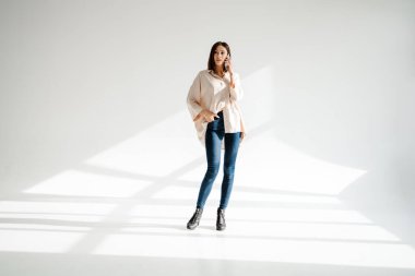 Elinde cep telefonu olan orta yaşlı bir kadının soyutlanmış arka planda dikilip konuşması.