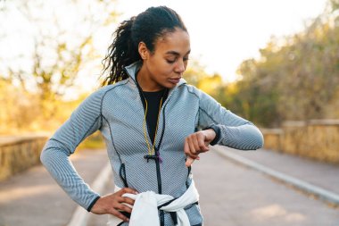 Odaklanmış Afro-Amerikan sporcu kadın parkta spor yaparken ukala bakışlara bakıyor.