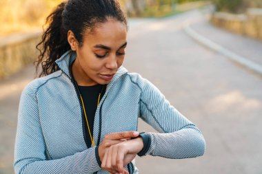 Odaklanmış Afro-Amerikan sporcusu. Parkta spor yaparken akıllı kaset kullanıyor.
