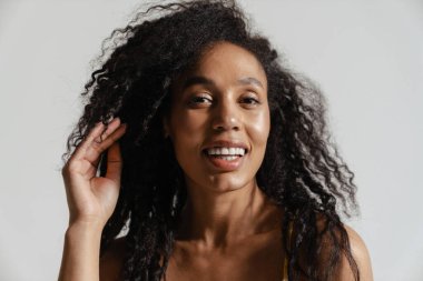 Siyah esmer kadın gülümsüyor ve beyaz arka planda izole edilmiş kameraya bakıyor.