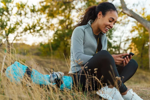 Glimlachen Afrikaans Amerikaanse Sportvrouw Met Behulp Van Mobiele Telefoon Terwijl — Stockfoto