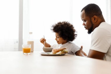 Siyah baba ve oğlu kahvaltı yaparken evde mutfaktaydılar.