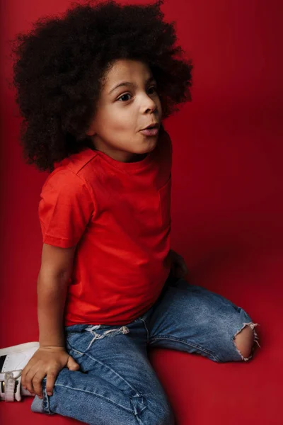 Kleine Afrikaanse Jongen Dagelijkse Kleding Rode Muur Achtergrond Zittend Een — Stockfoto